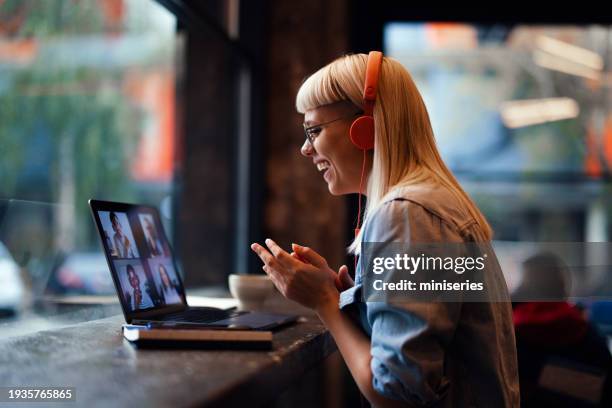 portrait d’une belle jeune femme joyeuse ayant une réunion en ligne sur son ordinateur portable à la cafétéria (espace de copie) - auto entrepreneur photos et images de collection