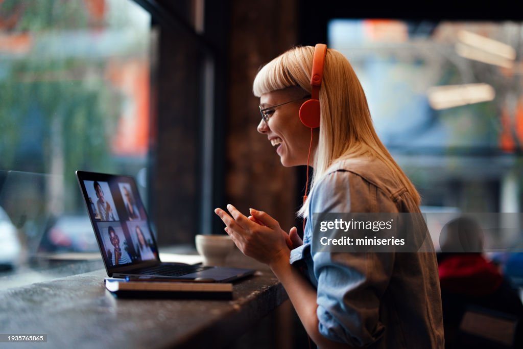 Portrait of a Cheerful Beautiful Young Woman Having an Online Meeting on Her Laptop in the Cafeteria (Copy Space)