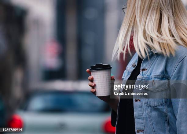 close up of an anonymous woman walking and holding a paper coffee cup - household equipment stock pictures, royalty-free photos & images