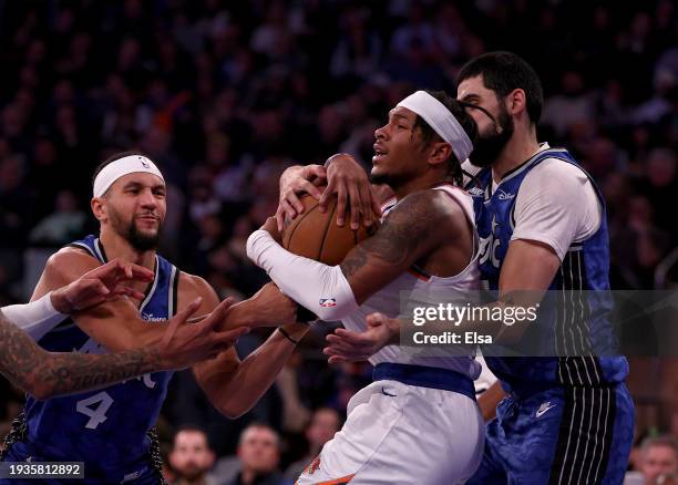 Miles McBride of the New York Knicks tries to keep the rebound as Jalen Suggs and Goga Bitadze of the Orlando Magic defend at Madison Square Garden...