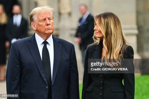 Former US President Donald Trump stands with his wife Melania Trump as they depart a funeral for Amalija Knavs, the former first lady's mother,...