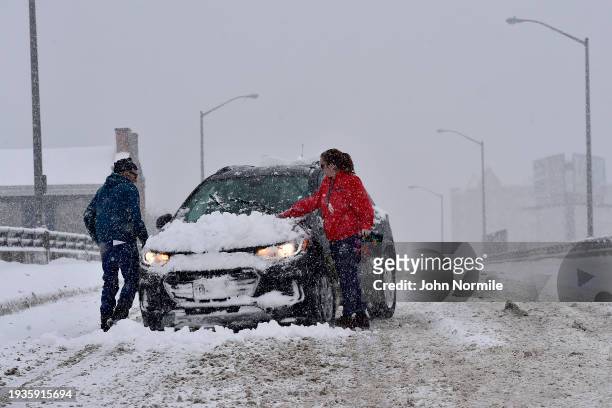 Driver and her passenger try to clear snow from their windshield along Louisiana Street on January 18, 2024 in Buffalo, New York. Buffalo and its...