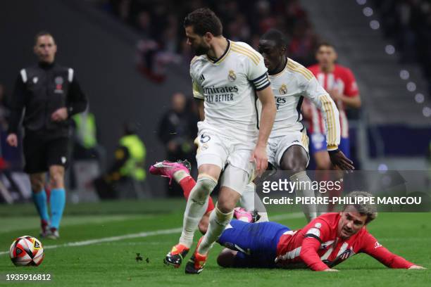 Atletico Madrid's French forward Antoine Griezmann falls down between Real Madrid's Spanish defender Nacho Fernandez and Real Madrid's French...