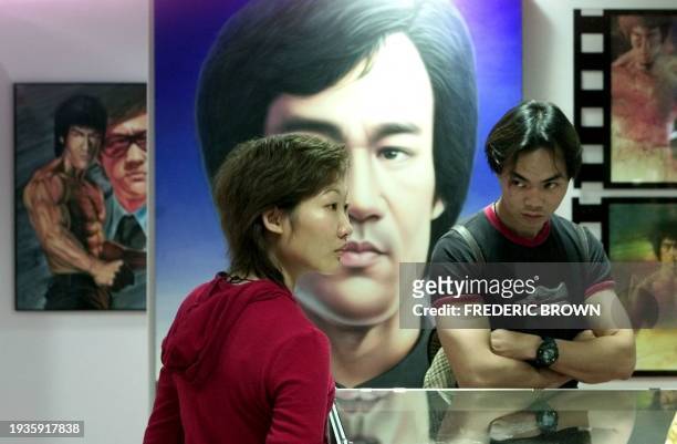 Visitors stand among artwork of martial arts star Bruce Lee at Dragon Expo 2000 in Hongkong, 27 November 2000, on what would have been Lee's 60th...