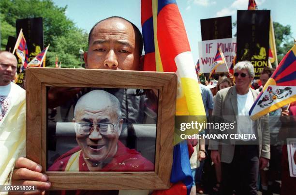 Tibetan monk Yeshi Tokden holds up a picture of the Dalai Lama as US actor Richard Gere and others march from Lafayette Park near the White House to...