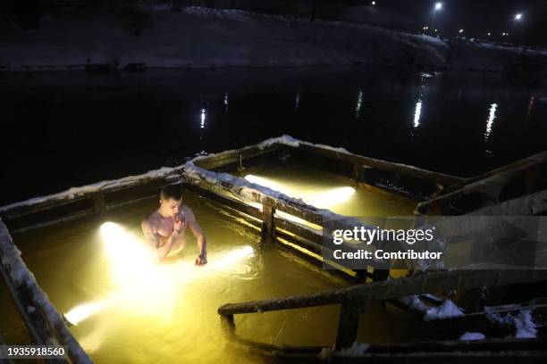 Russian Orthodox believer crosses himself in an ice water of the Istra river, marking the Epiphany, as the air temperature is minus 7 degrees celsius...