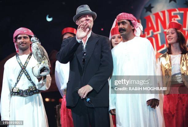 Actor Bruce Willis waves to the crowd gathered for the opening of the new Planet Hollywood restaurant in Dubai 26 May, as two Emiratis stand-by. The...