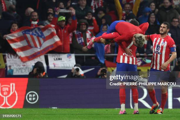 Atletico Madrid's French forward Antoine Griezmann is lifted by Atletico Madrid's Uruguayan defender Jose Gimenez after scoring his team's third goal...