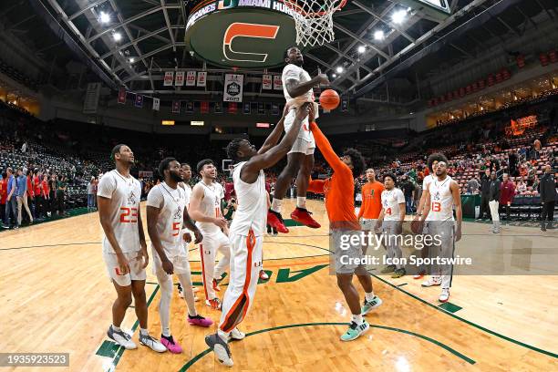 Miami center Michael Nwoko and forward Norchad Omier lift guard Bensley Joseph into the air to dunk as part of the team's pre-game rituals as the...