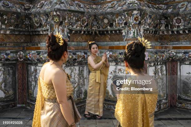 Chinese tourists in Thai traditional dress pose for photographs at Wat Arun Ratchawararam Rathawaramahawihan in Bangkok, Thailand, on Wednesday, Jan....