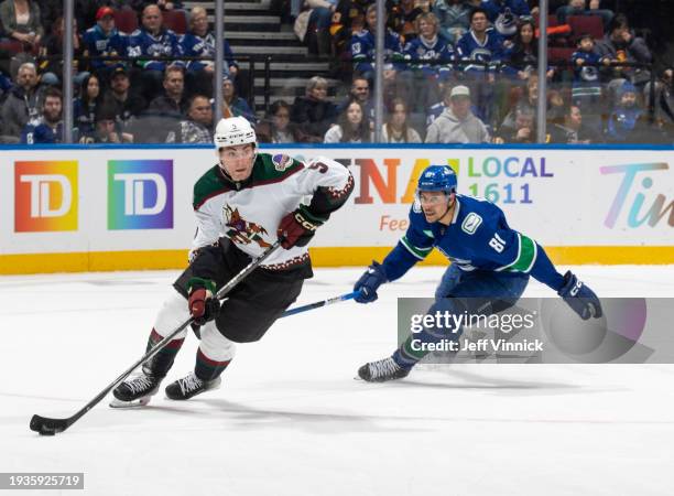 Dakota Joshua of the Vancouver Canucks and Michael Kesselring of the Arizona Coyotes battle for the puck during the second period of their NHL game...