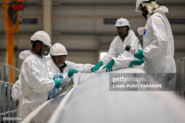 This photograph taken on January 11 shows employees working on blades for wind turbines produced at an Adani Group factory in Mundra. Deep in the...