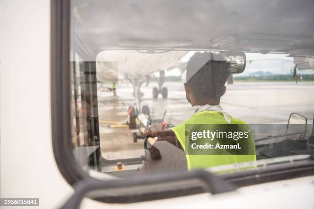 junger schwarzer mann fährt einen lkw in der nähe eines flugzeugs - flugzeugmechaniker stock-fotos und bilder