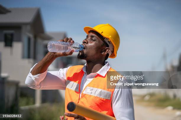 the construction workers are drinking water thirstily due to the scorching hot weather. - thirsty photos et images de collection