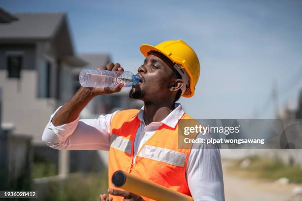 the construction workers are drinking water thirstily due to the scorching hot weather. - thirst project imagens e fotografias de stock