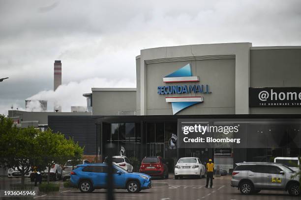 Chimneys at the Sasol Ltd. Secunda synthetic fuel plant beyond a shopping mall in the town of Secunda, Mpumalanga province, South Africa, on...