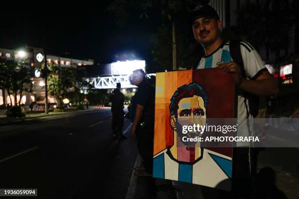 Man displays a painting of Argentine player Lionel Messi outside the Miami FC team's Real Intercontinental Hotel on January 19, 2024 in San Salvador,...