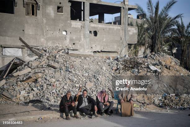 Palestinians are seen next to the rubble of a building destroyed by an Israeli attack while Israel's attacks continue on Gaza Strip as Palestinians...