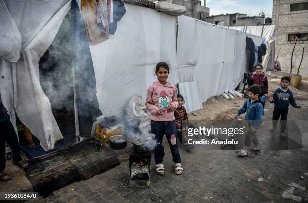 Palestinian children cook meal among the tents while Israel's attacks continue on Gaza Strip as Palestinians who took refuge in the city of Rafah are...