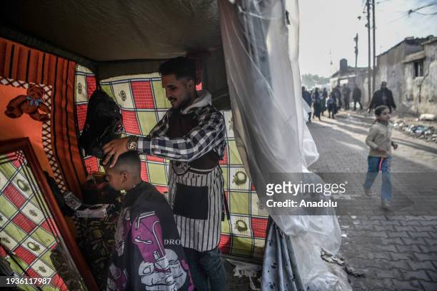 Palestinian barber cuts a client's hair while Israel's attacks continue on Gaza Strip as Palestinians who took refuge in the city of Rafah are trying...