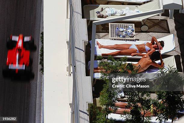 Ladies sunbathe as Michael Schumacher of Germany and Ferrari drives past during the Monaco Formula One Grand Prix held on May 26, 2002 in Monte...