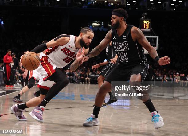 Caleb Martin of the Miami Heat drives against Royce O'Neale of the Brooklyn Nets during their game at Barclays Center on January 15, 2024 in New York...