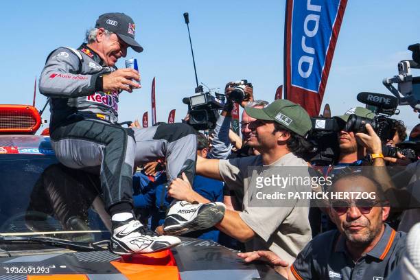 Team Audi Sport's Spanish driver Carlos Sainz is congratulated by his son Formula 1 driver Carlos Sainz Jr. After crossing the finish line of stage...