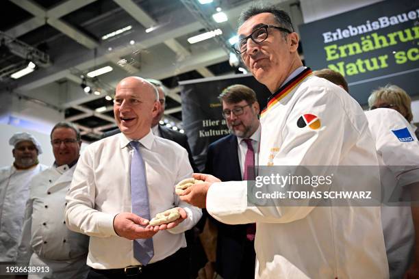 Berlin's Mayor Kai Wegner and German Agriculture Minister Cem Oezdemir pose with a self-made pretzel at the booth of the German bakers' guild during...