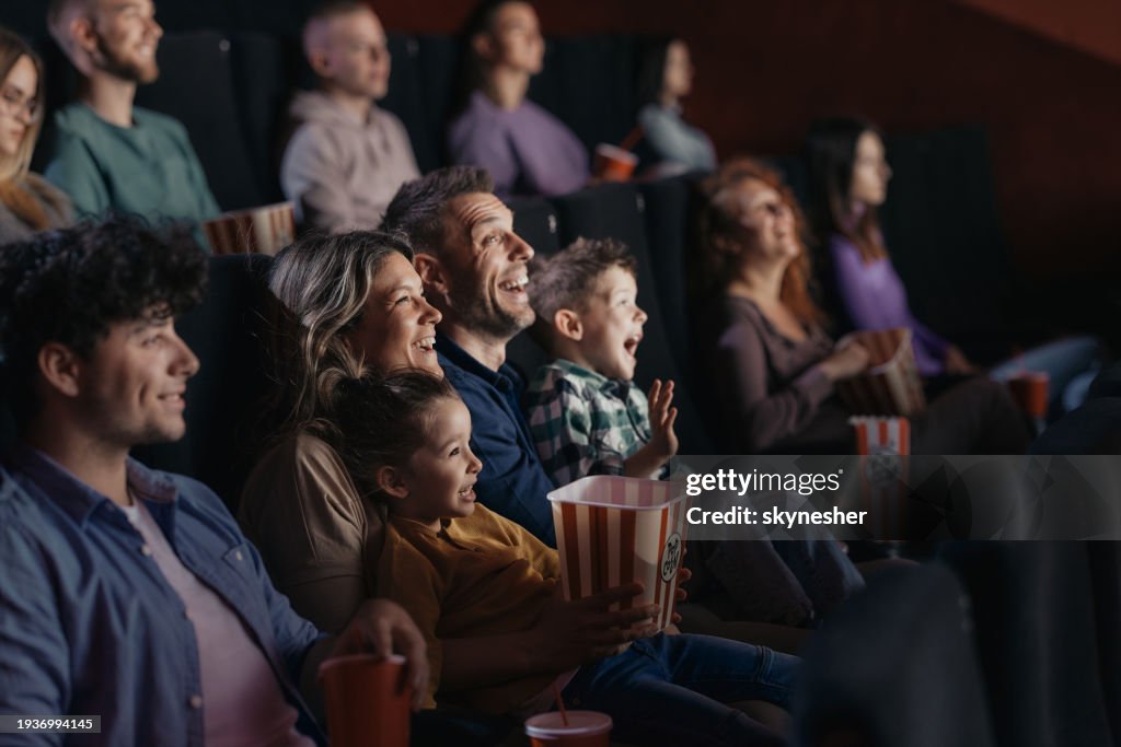 Cheerful family watching a funny movie in theatre.