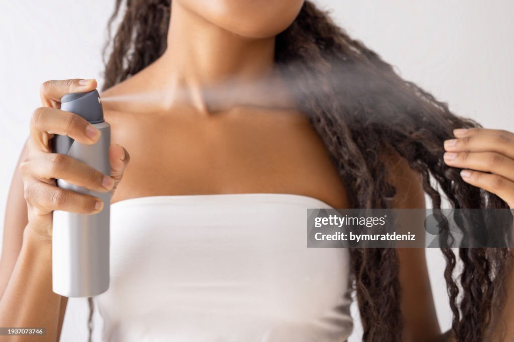 Woman putting hairspray on her hair