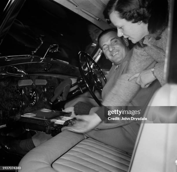 British singer Webster Booth is shown the interior of a Rolls Royce by Patricia Swain, director of her husband's HR Owen luxury car showroom at...