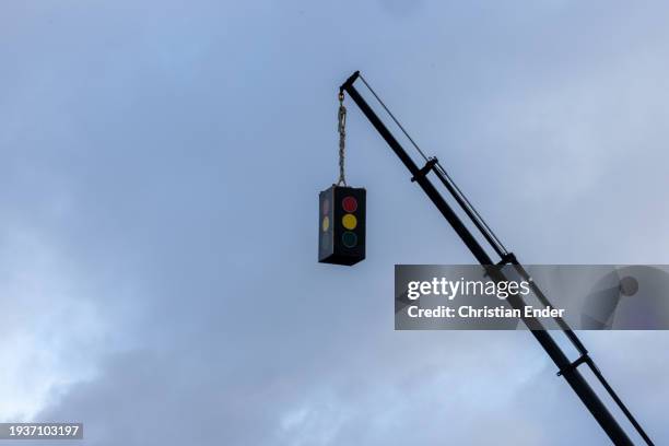 Traffic light, which is supposed to symbolize the government, hangs on a crane as protesting farmers arrive with their tractors to attend a...