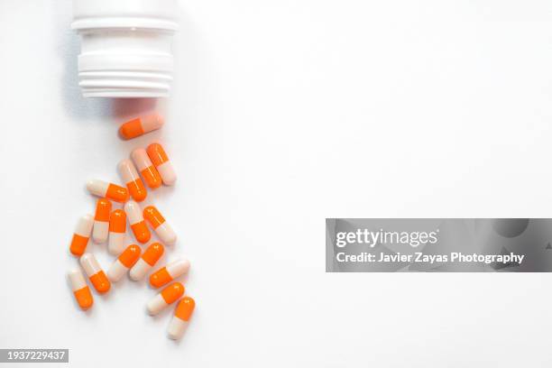 many orange and white pills on white background - comprimés photos et images de collection