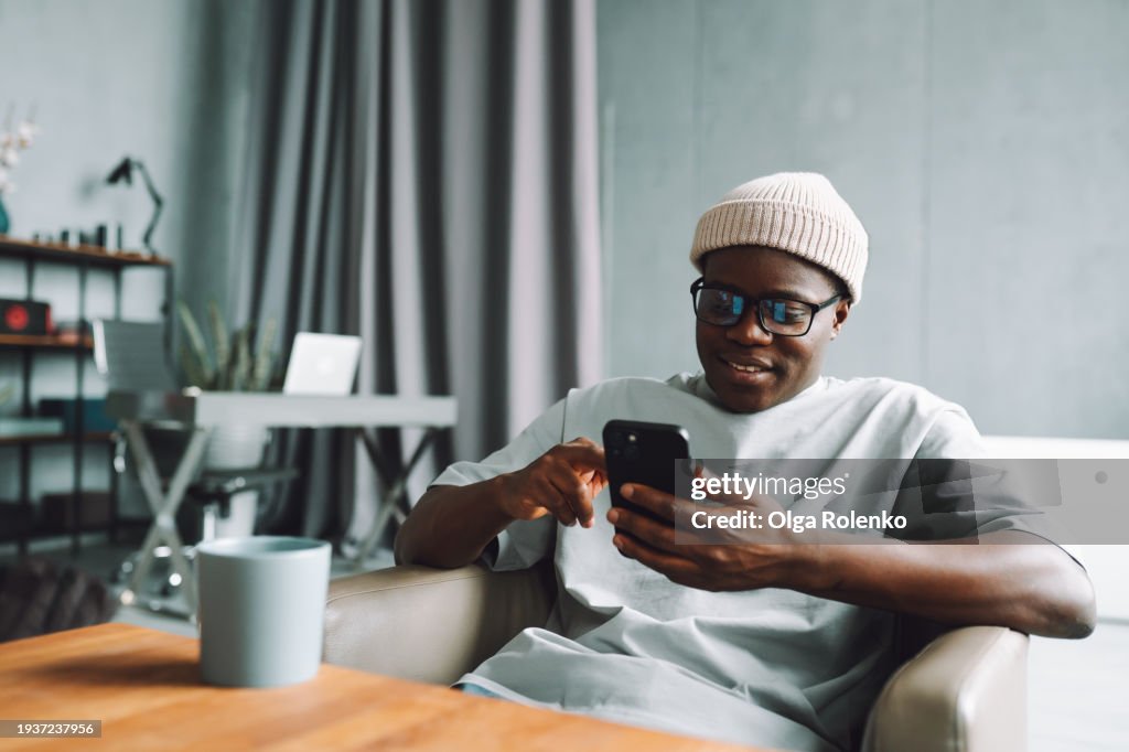 Online shopping. A man makes purchases on the Internet using a smartphone at home in the living room.