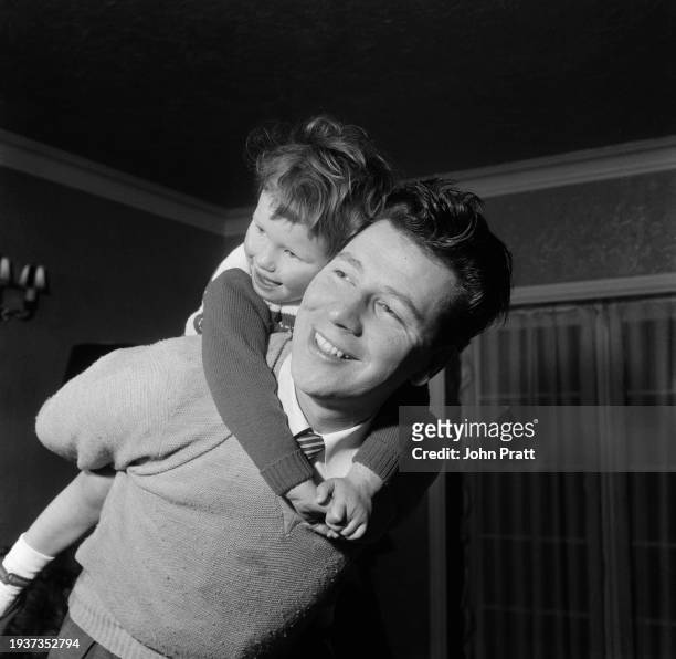 British variety performer and singer Max Bygraves gives his daughter Maxine a piggyback in their Edgware home, London, England, September 1954.