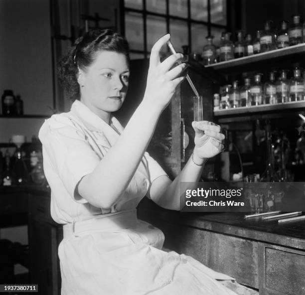 Medical student holding a long glass pipette and two test tubes at St Mary's Hospital Medical School in Paddington, London, England, October 1954.