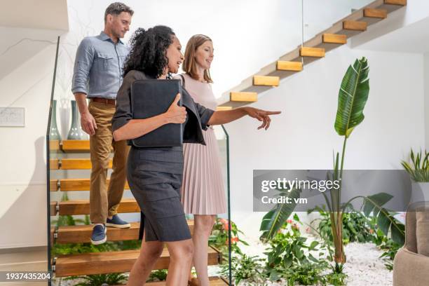 real estate agent and buyers walking downstairs - visita de inmuebles en venta fotografías e imágenes de stock