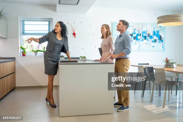 real estate agent showing kitchen to couple - visita de inmuebles en venta fotografías e imágenes de stock