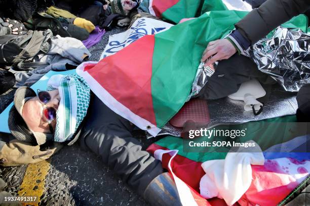 Supporter checks the hot-water bottles being used by one activist while they are locked on in the middle of the road during the demonstration....