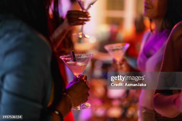 close up of a martini glass held by a female at a bar - nightlife bar stock pictures, royalty-free photos & images