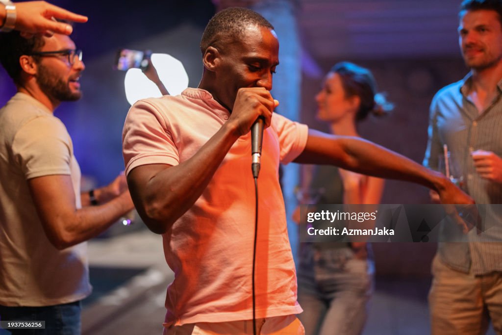 Un hombre negro cantando karaoke en una fiesta de verano