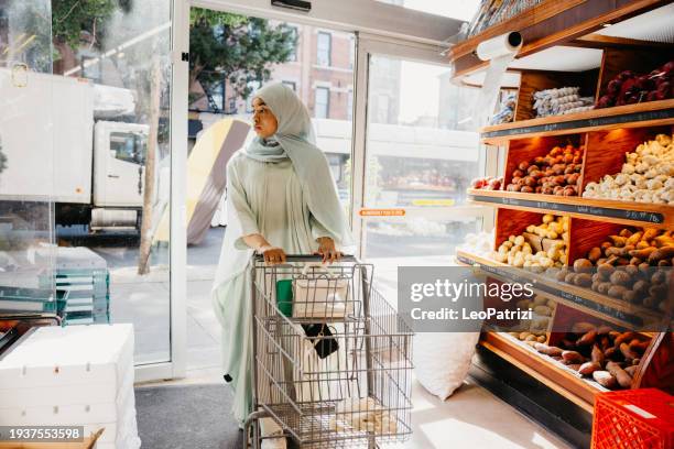 woman in abaya entering a grocery store in new york - halal stock pictures, royalty-free photos & images