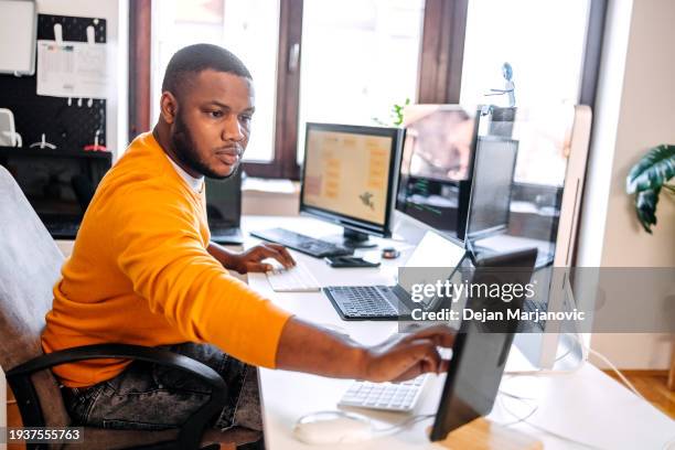 programmer sitting in front of computer screens and working as a freelancer at home settings - multiple screens stock pictures, royalty-free photos & images