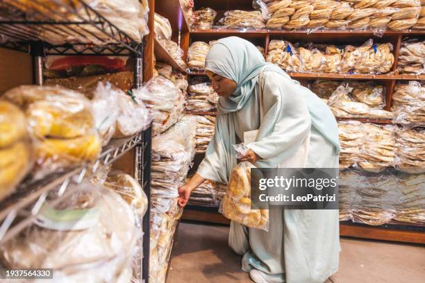 muslim woman buying pita bread in a grocery store - halal stock pictures, royalty-free photos & images