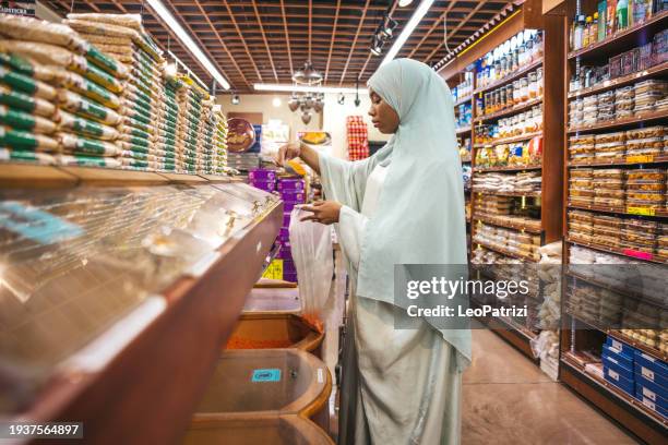 muslim woman buying spices in a halal grocery store - halal stock pictures, royalty-free photos & images