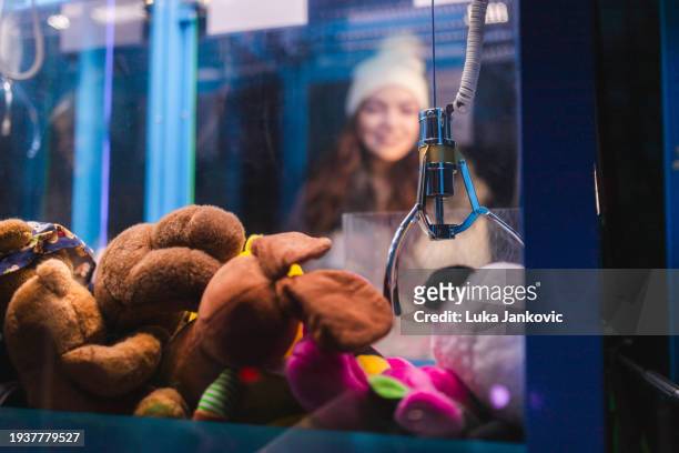 woman playing an arcade claw machine game - arcade machine stockfoto's en -beelden