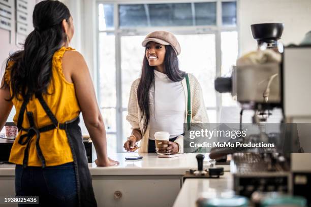young woman making a purchase in modern coffeeshop - bäckergesellenmütze stock-fotos und bilder