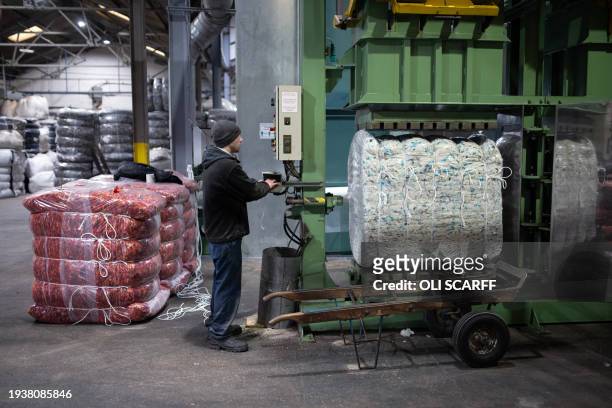 An employee at Mallalieus' mill packages a compressed bale of blended dyed wool fibres, in Delph, near Oldham, northern England on January 18, 2024....