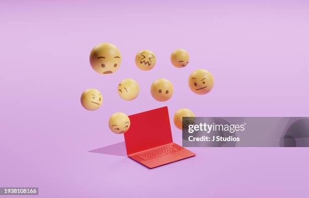 emojis hovering over a laptop - jaloezie negatieve emotie stockfoto's en -beelden