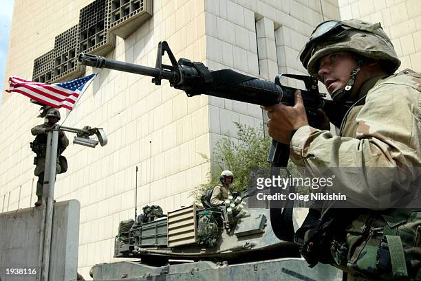 Soldier raises a flag while another soldier guards the street April 18, 2003 in Baghdad, |raq.
